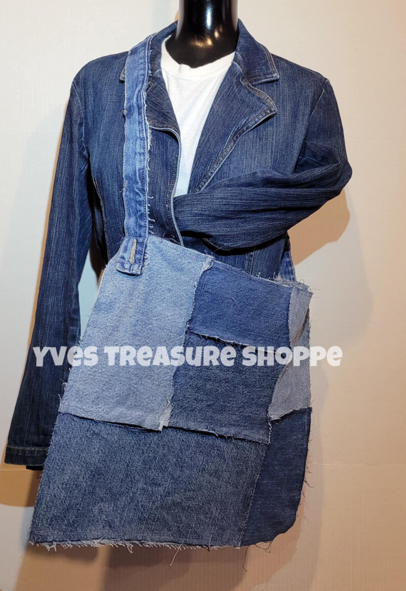 Denim jacket with patchwork design on a mannequin against a beige background, branded 'Yves Treasure Shoppe'.